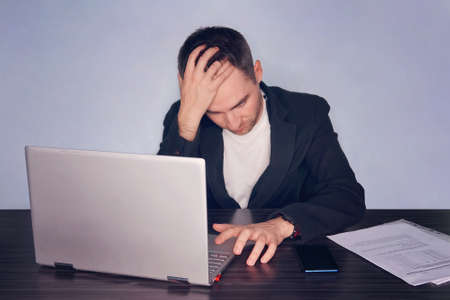 Serious frustrated businessman suffering from headache migraine at workplace. Feeling tired...