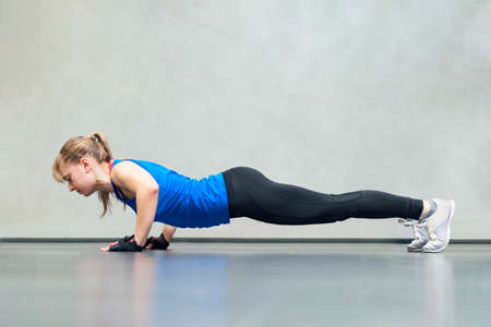 Gorgeous blonde woman warming up and doing some push ups a the gym. Sports concept healthy lifestyle...