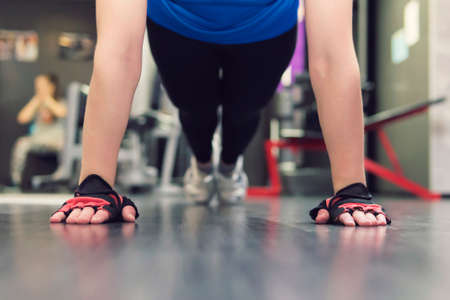 Close up hand of woman doing push ups in the gym. Training girls in the hall. Gloved hands on the floor in close-up. mitaines.の写真素材
