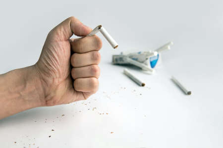 Broken cigarette in man hands, Stop smoking. Guy breaks a cigarette with fingers on white background. The harm of Smoking. To quit Smoking.の写真素材