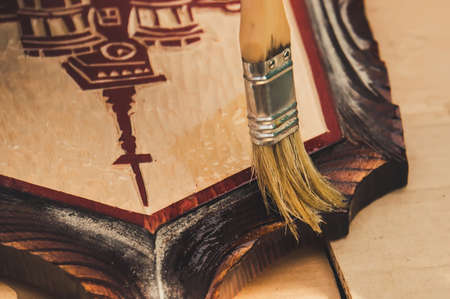 A woman covers varnished wooden kitchen Board. Hand with brush closeup.の写真素材