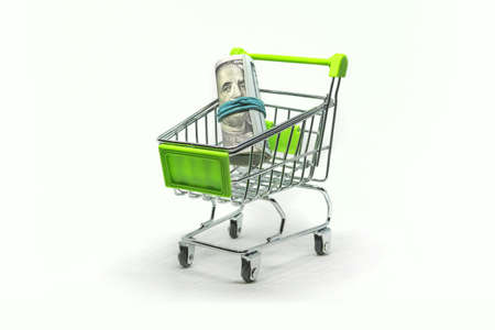 buying U.S. currency. close up dollar banknote in mini shopping cart toy, green small basket trolley. business and money Saving for shopping concept.の写真素材