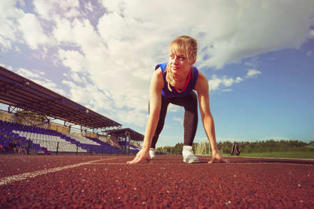 Race Fit confident woman in starting position ready for running. Female athlete about to start a...