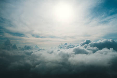 a view from high above the clouds. View of the clouds from the window of the aircraft. Non-flying weather. The sun shines through the dark blue and gray cloudsの写真素材