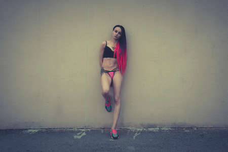 Sad half-naked girl with pink pigtails. beautiful brunette woman sexy girl standing on a city street, prostitution, slums. grain in the photo is an artistic effect.の写真素材