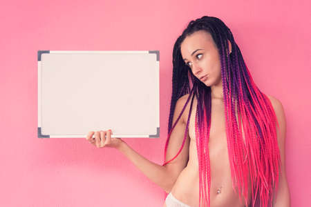 Your text here. Pretty young excited woman holding empty blank board. Sexy naked brunette holding empty board. An informal stripper teacher.の写真素材