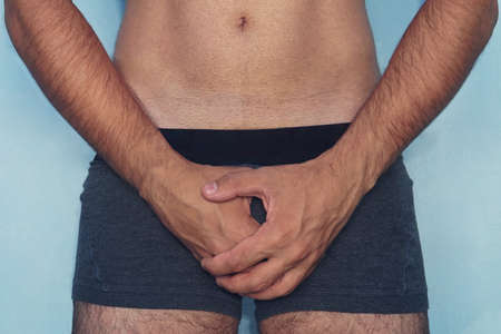Handsome man is using his hands closing his penis. Attractive man gets painful of mind, he can t has...