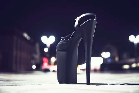 Extremely high heeled fetish shoes, one black Shoe stands on the asphalt on the road in the city.の写真素材