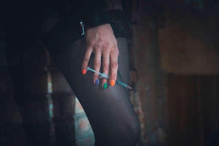 A prostitute with a drug addiction is holding a syringe with a dose of heroin. Social problems of our time. the concept of addiction and bad habitsの写真素材