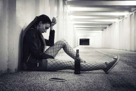 Alcoholism and hangover. Brunette young female suffering from terrible headache. Depressed young girl, alcohol drug addict lost in thoughts. loneliness, toper, drunkard, drinker. black and white photoの写真素材