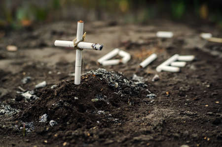 ash and cigarette look like grave and cross, art concept for world no tobacco day. The dangers of nicotine to health. The word die from cigarette butts.の写真素材