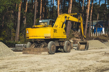 excavator at sandpit during earthmoving works. Yellow excavator on wheels.の写真素材