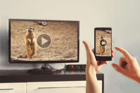 Closeup of a smart phone is connected to a smart TV. Views of videos from your phone to the TV. Use...
