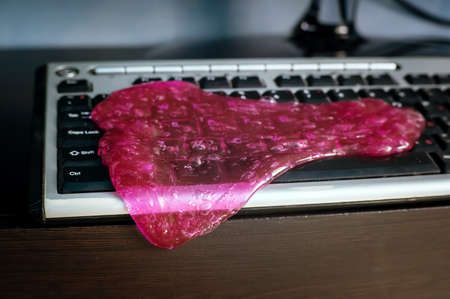 Keyboard cleaning gel is laying on the notebook. pink gel.の写真素材