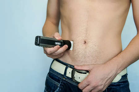 closeup of a young man trimming the hair of his pubis with an electric trimmer. concept of a clean healthy body for men. Man haircut pubic hair with a clipperの写真素材