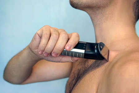 man, shaved, hariy chest. Man shaving his chest with trimmer, closeup of body.の写真素材