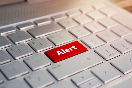 alert word on red keyboard button. Color button on the gray silver keyboard of modern ultrabook. caption on the buttonの写真素材