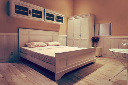 White wooden bed with white linens. Stylish interior design in bright colours. Expensive room in a...