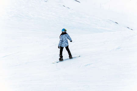 Snowboarder downhill on snowy off-piste slope in the evening light winter.の写真素材