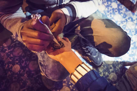 Artist applying beautiful henna tattoo Arabic design to a Woman's or Indian bride's hands at City Palace on wedding in Rajasthan. Mehndi is a popular body art among women of India, Pakistan, Africa.の写真素材