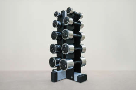 black metal stand with a chrome dumbbell on white background. Dumbbells of different weight category. Dumbbells with different weightsの写真素材