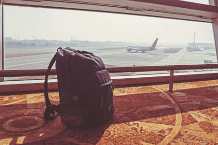 Silhouette of luggage or suitcase placed at the window at waiting terminal in international airports with the airplan taking off behide the building.の写真素材