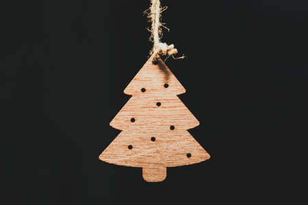 Wooden Christmas tree toy in the form of a Christmas tree hanging on a black background.の写真素材