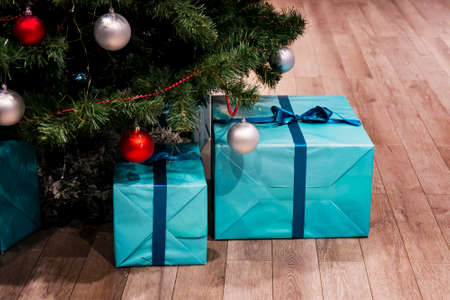 Christmas green tree with decorations and presents under it in loft interior. Large blue boxes in a gift wrap with a ribbon. real natural spruceの写真素材