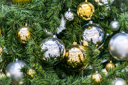 Decoration hanging from a christmas tree. Gold and silver balls hanging on the green Christmas tree closeupの写真素材