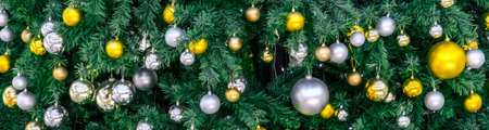 Decoration hanging from a christmas tree. Gold and silver balls hanging on the green Christmas tree closeupの写真素材