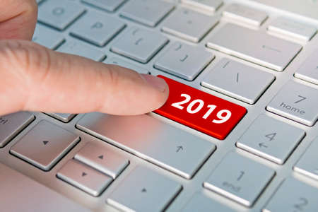 finger pressing keyboard key written 2019 newyear. finger presses a button on the gray keyboard. Beginning of new yearの写真素材
