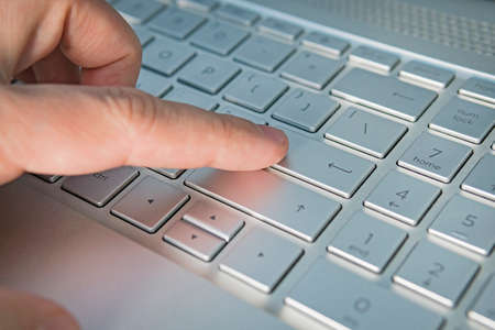 Close-up of typing male hands. grey silver keyboard button close up, Finger presses the enter button. English language and red light keyboard for hacker, gamer, office concept, soft focusの写真素材