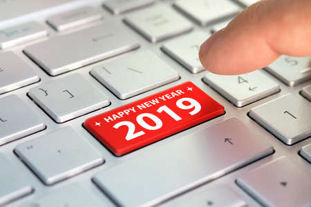 Keyboard with text HAPPY 2019 and finger pushing the enter button. Color button on the gray silver keyboard of modern ultrabook. caption on the button.の写真素材