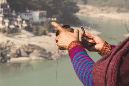 Woman with incense in hand making Puja in front of Holy river Ganges Rishikesh Indiaの写真素材