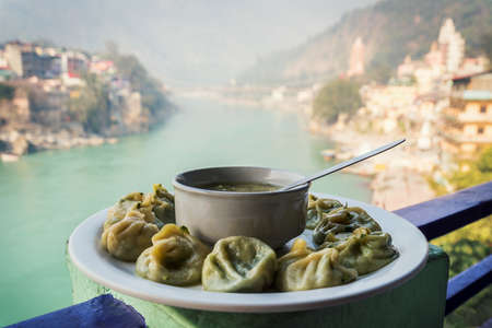 A large plate with the Tibetan Momo and hot soup on the background of the river Ganges. Rishikesh...