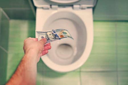 concept of senseless waste of money, loss, useless waste, large water costs, in the toilet wash a thousand dollars bill.の写真素材