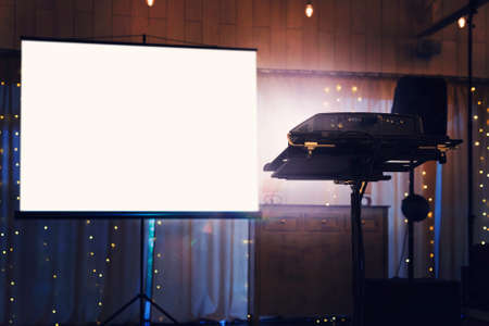 Blank projector screen mockup on the wall. Projection light in darkness. Projector display mock up. Presentation clear monitor on wall. Slide show front design. Slideshow billboard banner frameの写真素材