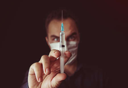 Out of focus doctor with syringe in a dark backgroundの写真素材