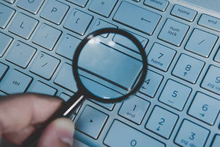 Blank button of laptop keyboard magnidied through the magnifying glass. Wordless key of a computer keypad viewed through the loupe. Write your text on computer keyboard. Concept of internet surfing.の写真素材