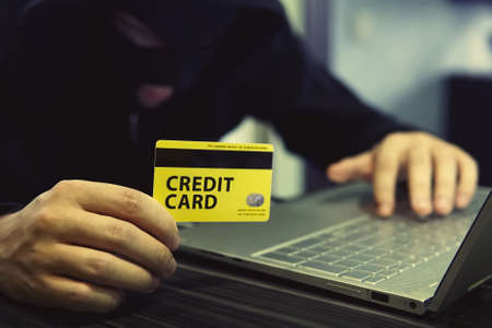 Unknown person uses computer and credit card to commit cyber crime. Computer trespasser uses internet to steal money. Drawing money from banking account by payment card fraud. Hacking online banking.の写真素材