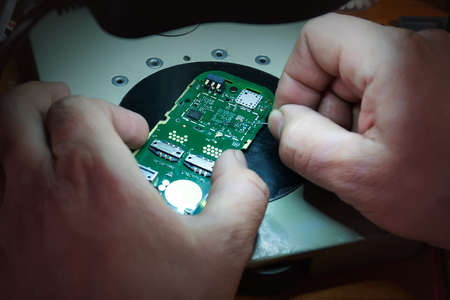 Close-up photos showing process of mobile phone repair. Phone repair under the microscope. Mobile fee. repair gadgets at home closeup. Male hands check the performance of the phoneの写真素材