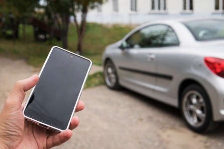 Mobile phone apps for car owners concept. Man using smart phone to check status, control his new car. Blank Empty mobile phone screen for designの写真素材