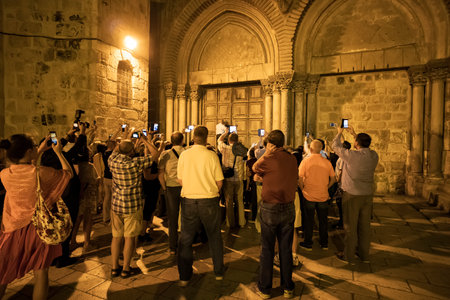 JERUSALEM, ISRAEL. 24 October 2018: tourists take pictures on smartphones ritual of closing doors of the Church of Holy Sepulchre. Muslim key holder locks the doors.のeditorial素材