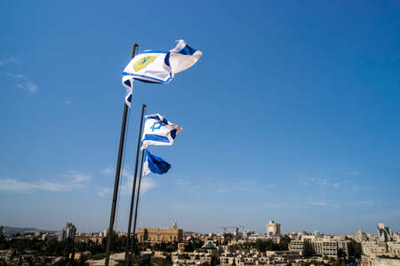 Israel and Jerusalem flags on Jerusalem old city walls against the blue sky with white clouds in the Sunny summer lightの写真素材