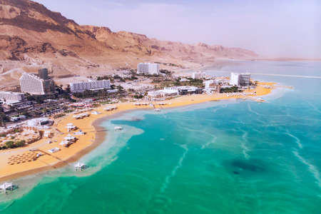 Blue water dead sea in the foreground on the background of the resort town of Ein Bokek in the middle of the desert in Israel. People tourists bathe in salt water. Useful Spa treatments. afternoonの写真素材