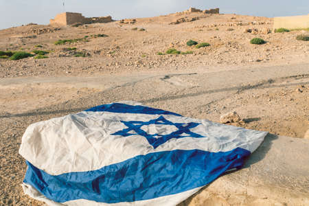 Left on a stone Israeli flag on the background of the Ancient fortress Masada Israel. patriotism, nationalism, Patriotic feeling.の写真素材