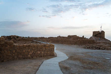 The tallest tower of Masada against the cloudy sky at dawn in the sun. Historical excavations on the ruins of the ancient era. Israelの写真素材
