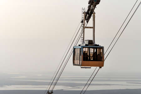cable car lifts tourists to the mountain fortress of Masada. Funicular on the background of the Judean desert, the dead sea and the cloudy sky. Desert beautiful landscape.の写真素材