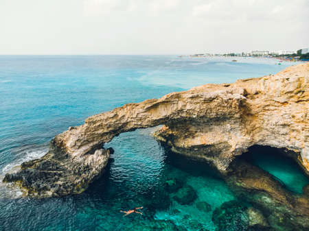 The bridge of love or love bridge is located in one of the most beautiful tourist attractions in Ayia Napa, Cyprus. girl is engaged in snorkeling, swimming with a mask. Coral and stone coast,の写真素材