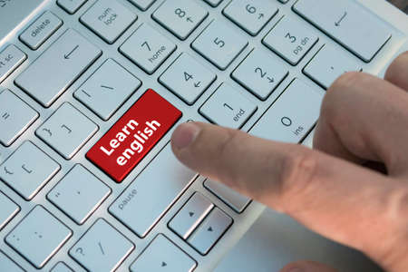 Closed up finger on keyboard with word LEARN ENGLISH. , Red button. inscriptions on the grey silver keyboard button close upの写真素材